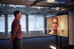Man stood infront of a screen showing his avatar