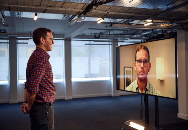 Man stood infront of a screen showing his avatar